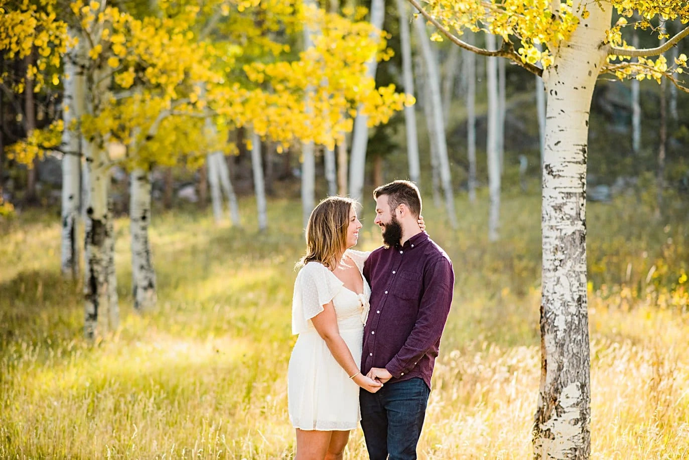 Couple in golden aspen grove couple walks in aspen grove in fall at RMNP engagement session by Boudler engagement photographer Jennie Crate