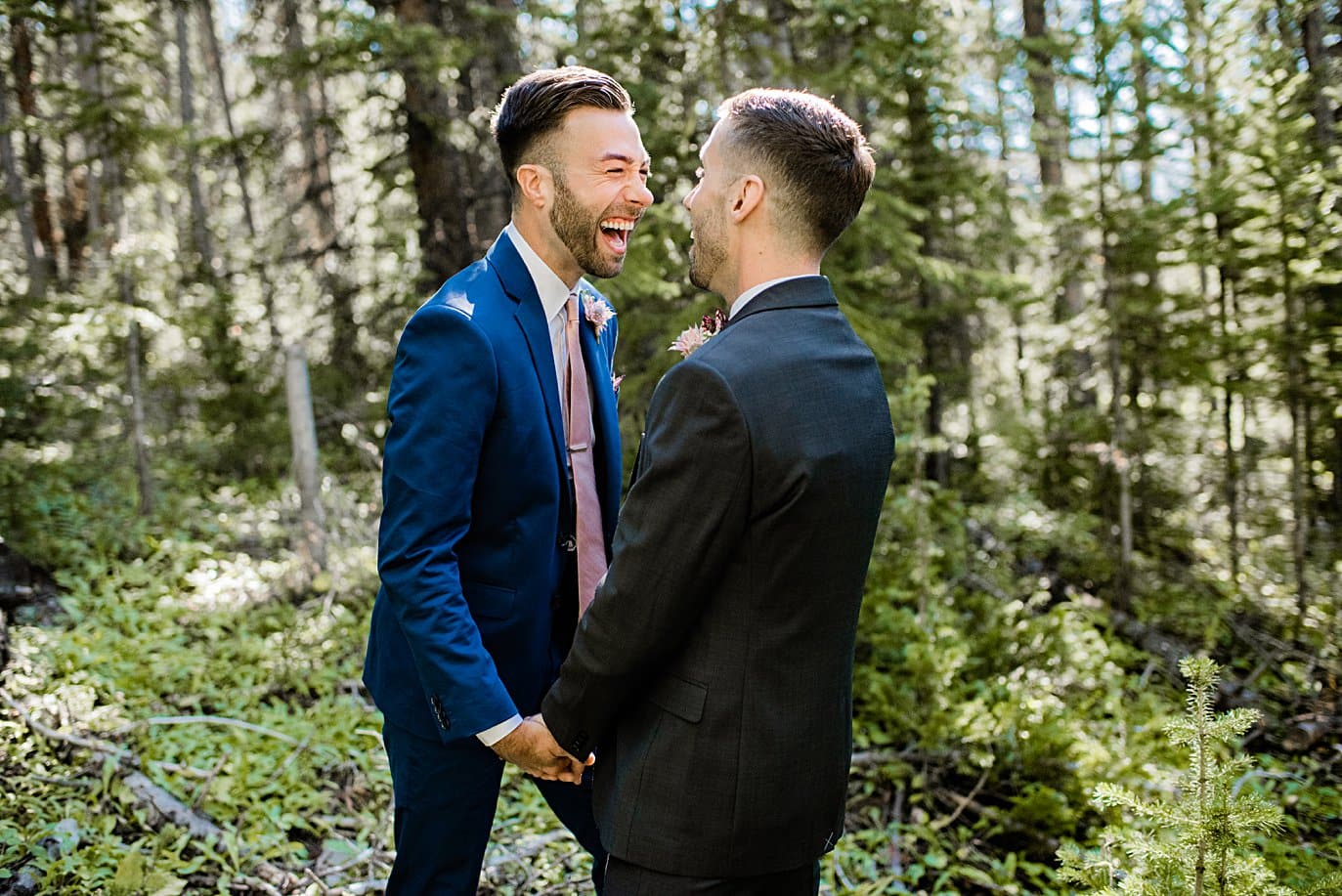 two grooms laughing in trees at Boras Pass elopement by Breckenridge elopement photographer Jennie Crate