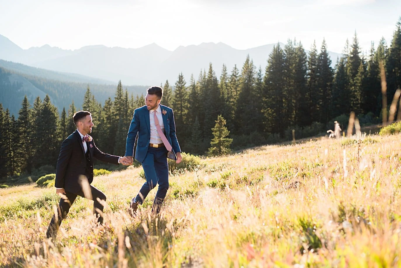 two grooms walk in meadow after self-solemnized ceremony at Breckenridge Elopement by Colorado gay wedding photographer Jennie Crate