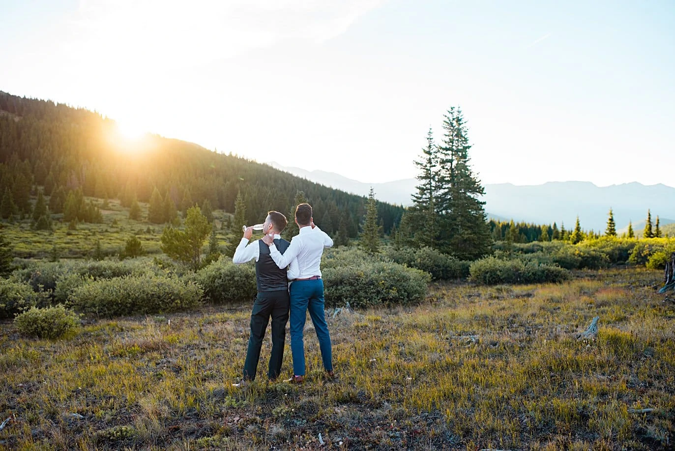 grooms enjoy champagne at sunset at top of Boreas Pass at sunset by Denver Elopement photograpeher Jennie Crate