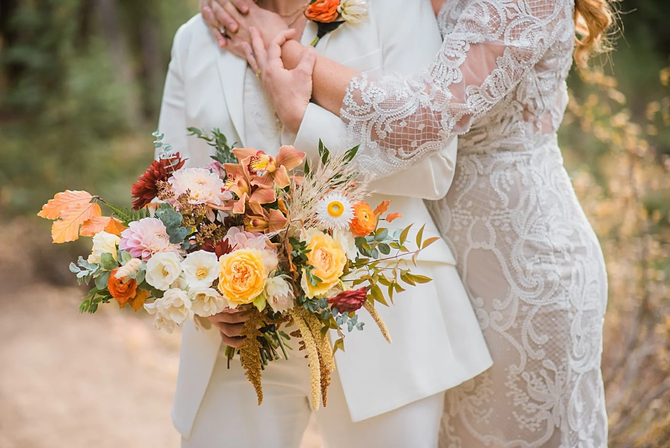 bride in dress with bride in suit and colorful bridal bouquet at Breckenridge microwedding by Colorado LGBT wedding photographer Jennie Crate