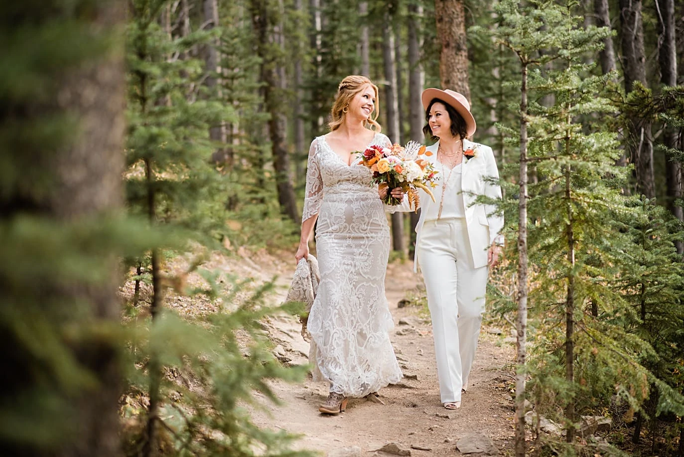 two brides walk through woods at Breckenridge microwedding by Colorado LGBT wedding photographer Jennie Crate