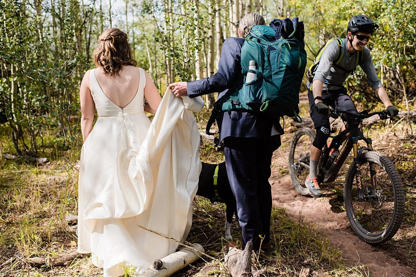 bride and groom hike past mountain biker on way to ceremony spot in Crested Butte for private elopement by Aspen wedding photographer Jennie Crate
