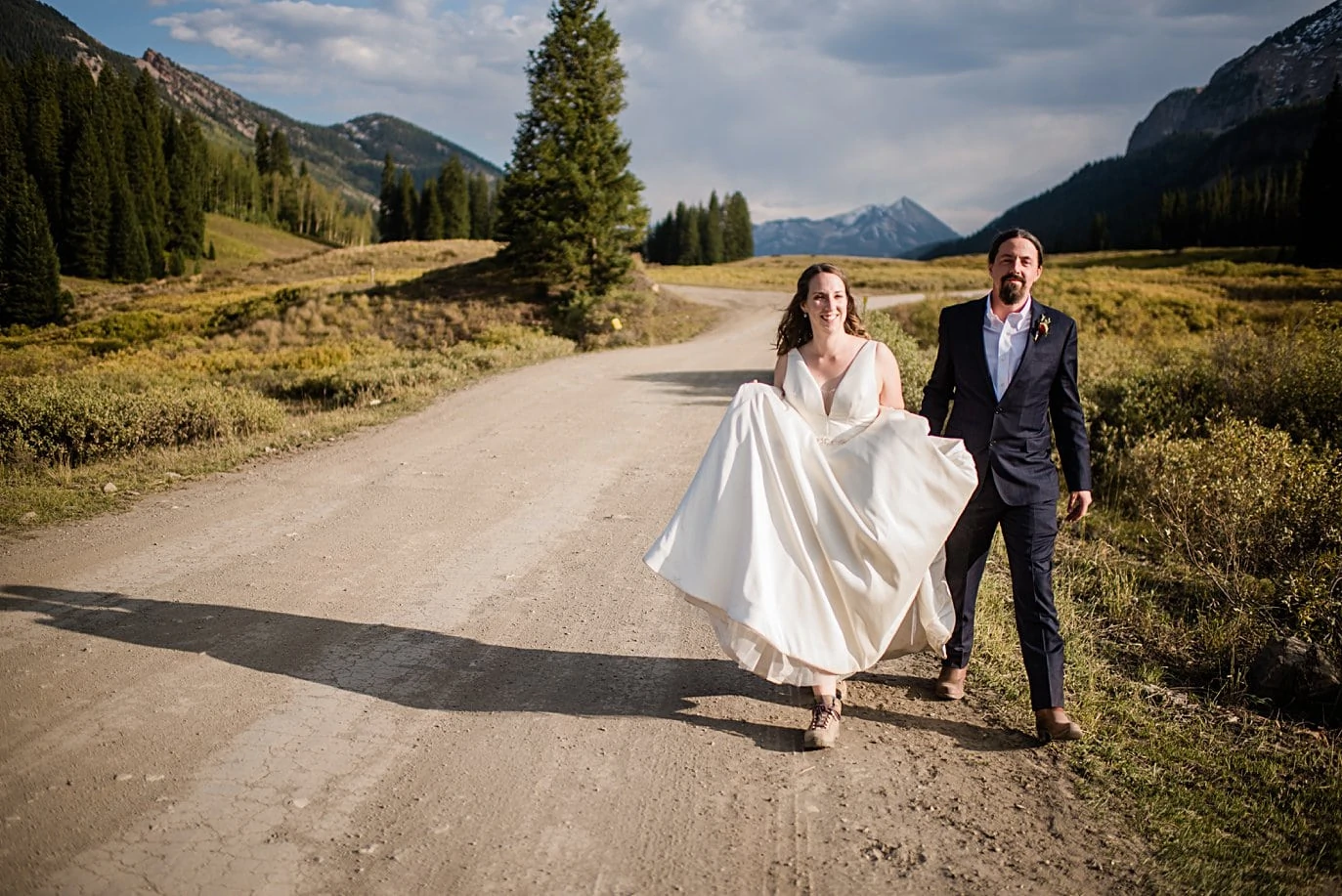 bride and groom walk down road on Gothic Pass at Crested Butte elopement by Denver wedding photographer Jennie Crate
