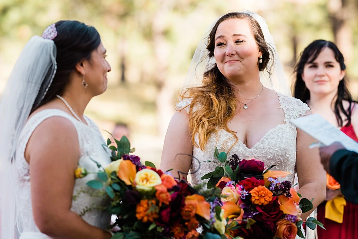 brides look at each other with emotion at start of wedding ceremony at fall Deer Creek Valley Ranch wedding by Denver wedding photographer Jennie Crate