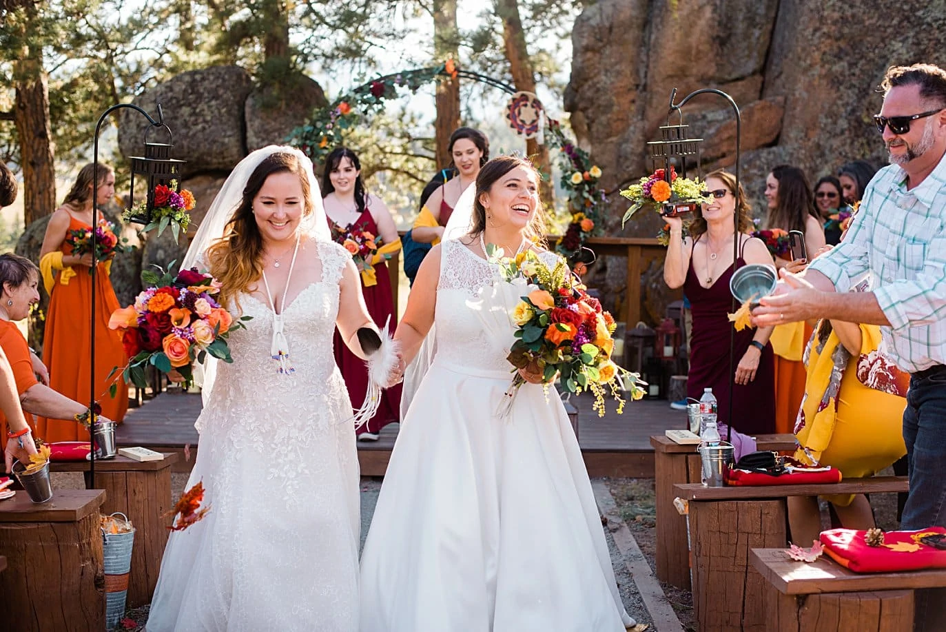two brides exit ceremony to shower of leaves at fall Deer Creek Valley Ranch wedding by Boulder wedding photographer Jennie Crate