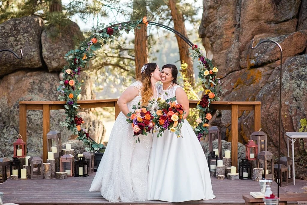 two brides in dresses at ceremony spot at the homestead at LGBT wedding by Colorado LGBT wedding photographer Jennie Crate