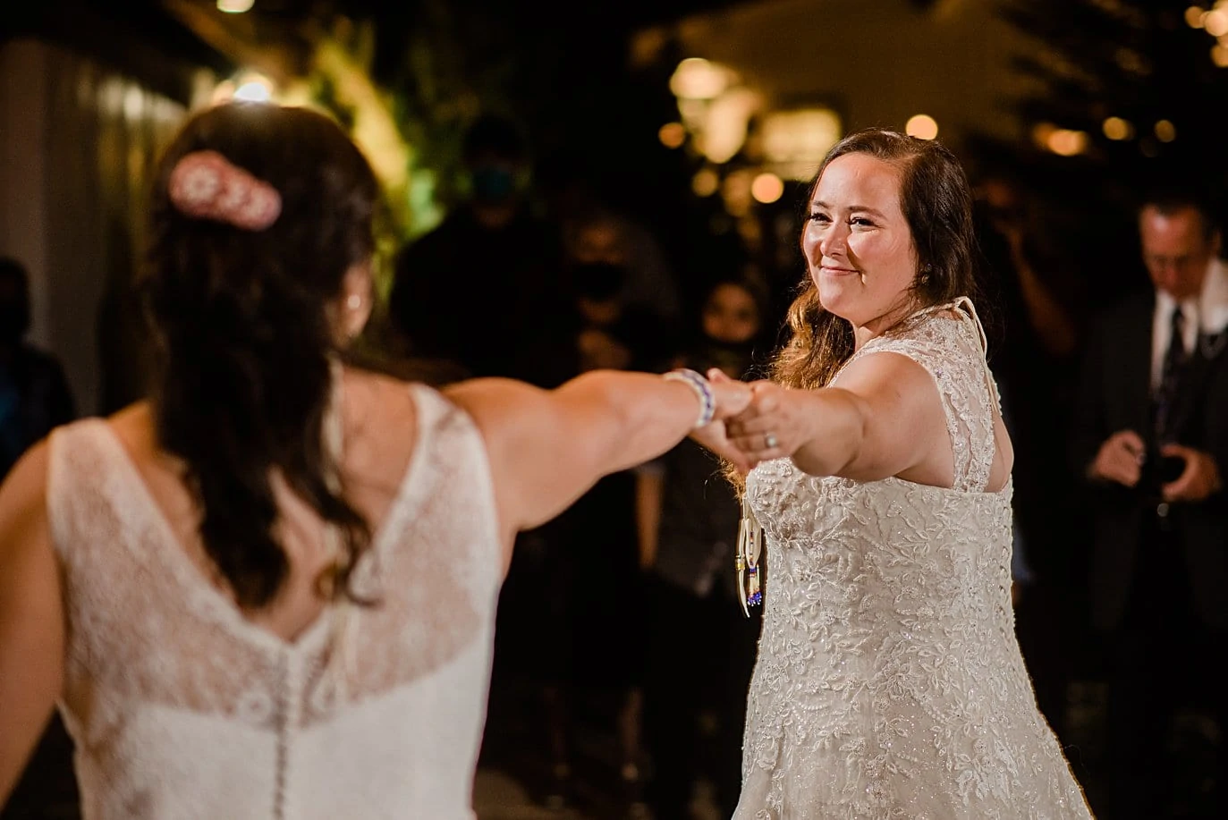 first dance on patio under market lights for two brides at Deer Creek Valley Ranch same-sex wedding by Denver LGBT wedding photographer Jennie Crate