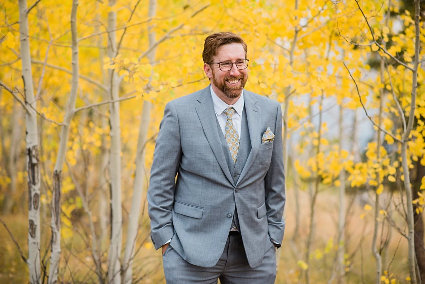 room in grey suit flanked by yellow aspens in fall in Golden Gate Canyon by Colorado gay wedding photographer Jennie Crate