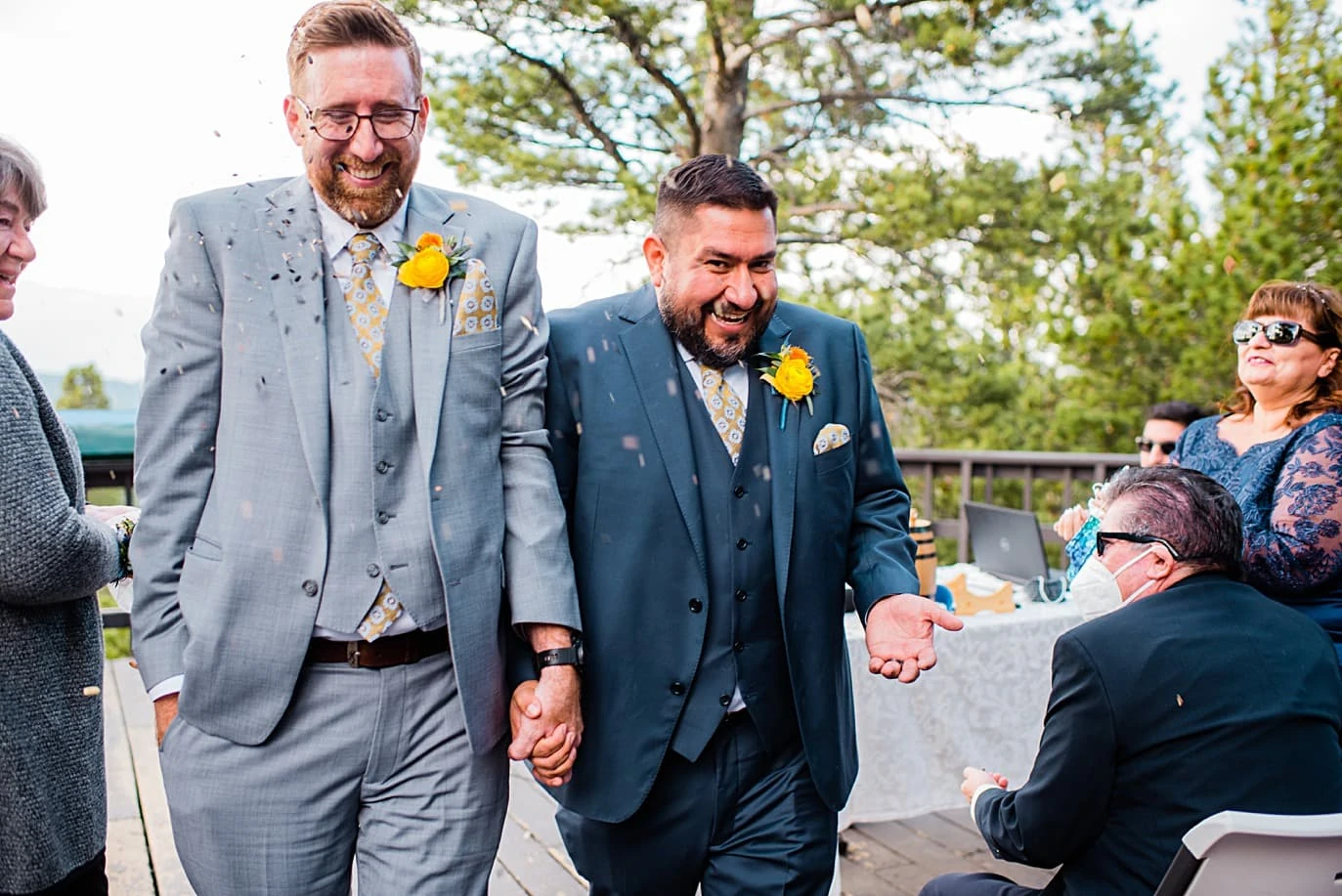 grooms walk down aisle to shower of birdseed at Panorama point during LGBTQ wedding by Colorado LGBT photographer Jennie Crate
