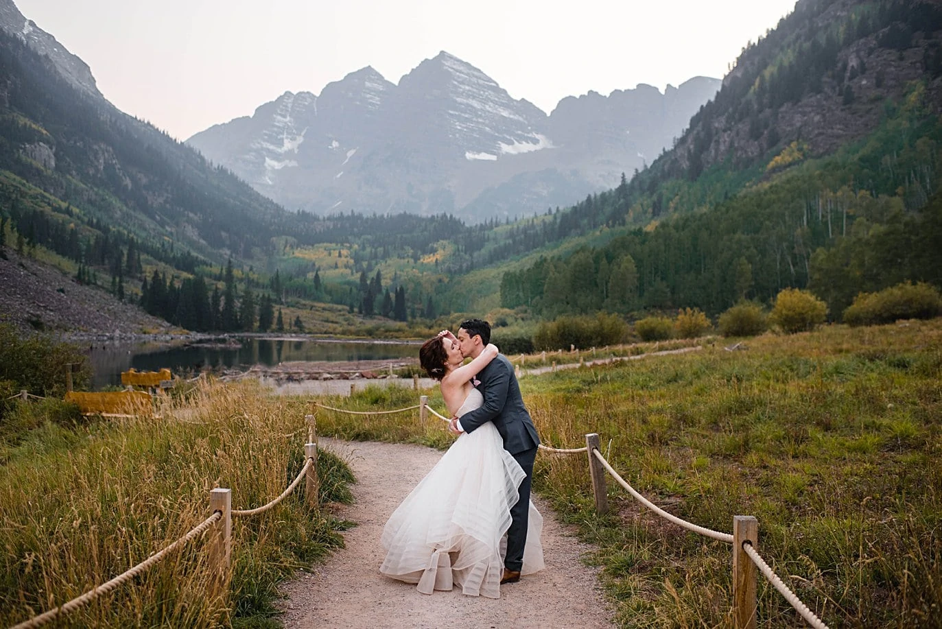 bride and groom kiss on path at Maroon Lake in fall wedding in Aspen by Denver wedding photographer Jennie Crate