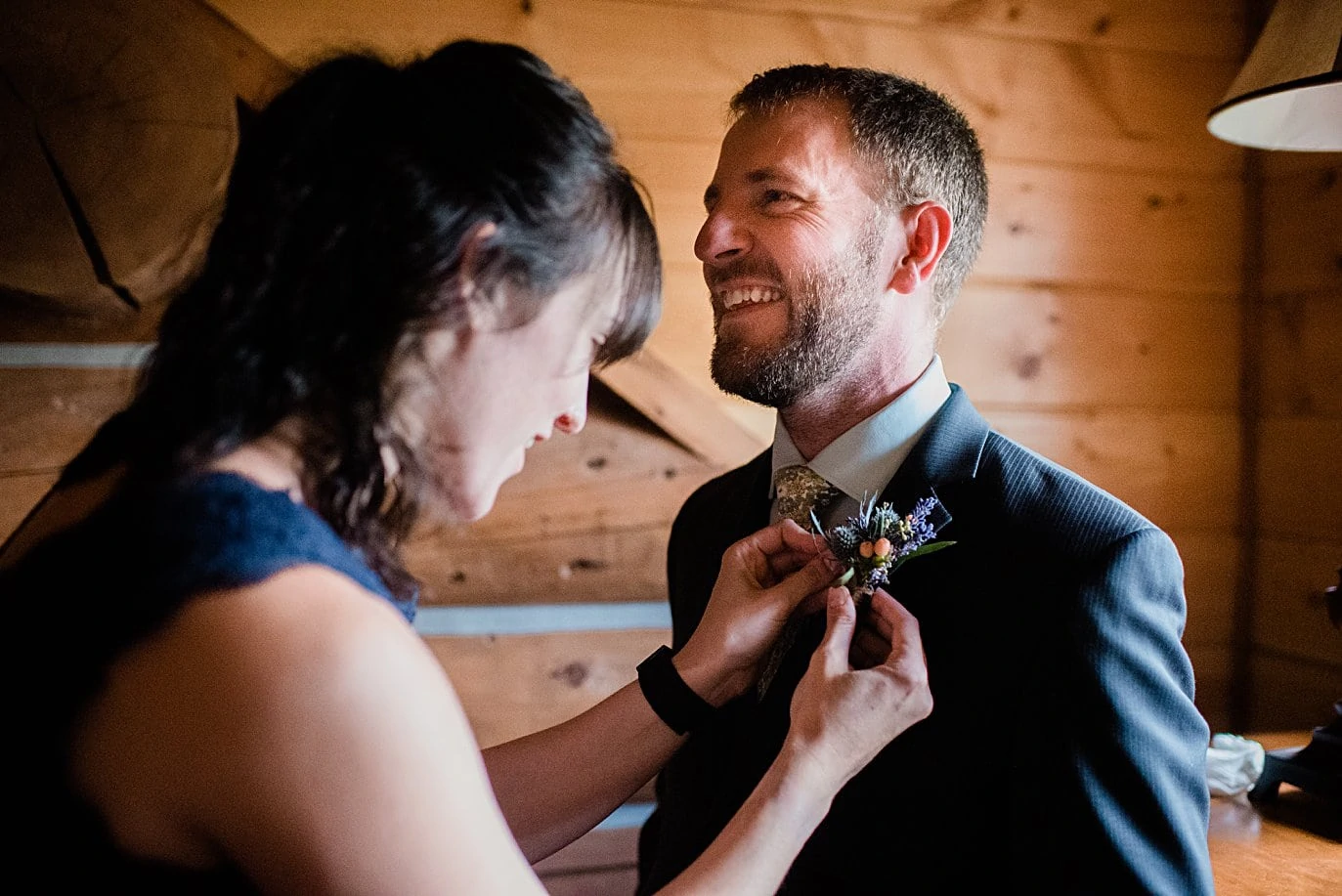 groom getting boutonniere pined on before wedding ceremony at intimate Grand Lake wedding by Grand Lake wedding photographer Jennie Crate