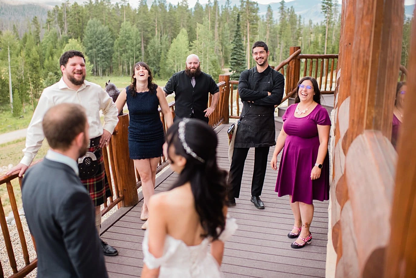 bride and groom talk with friends on porch before ceremony at intimate Grand Lake wedding by Denver wedding photographer Jennie Crate