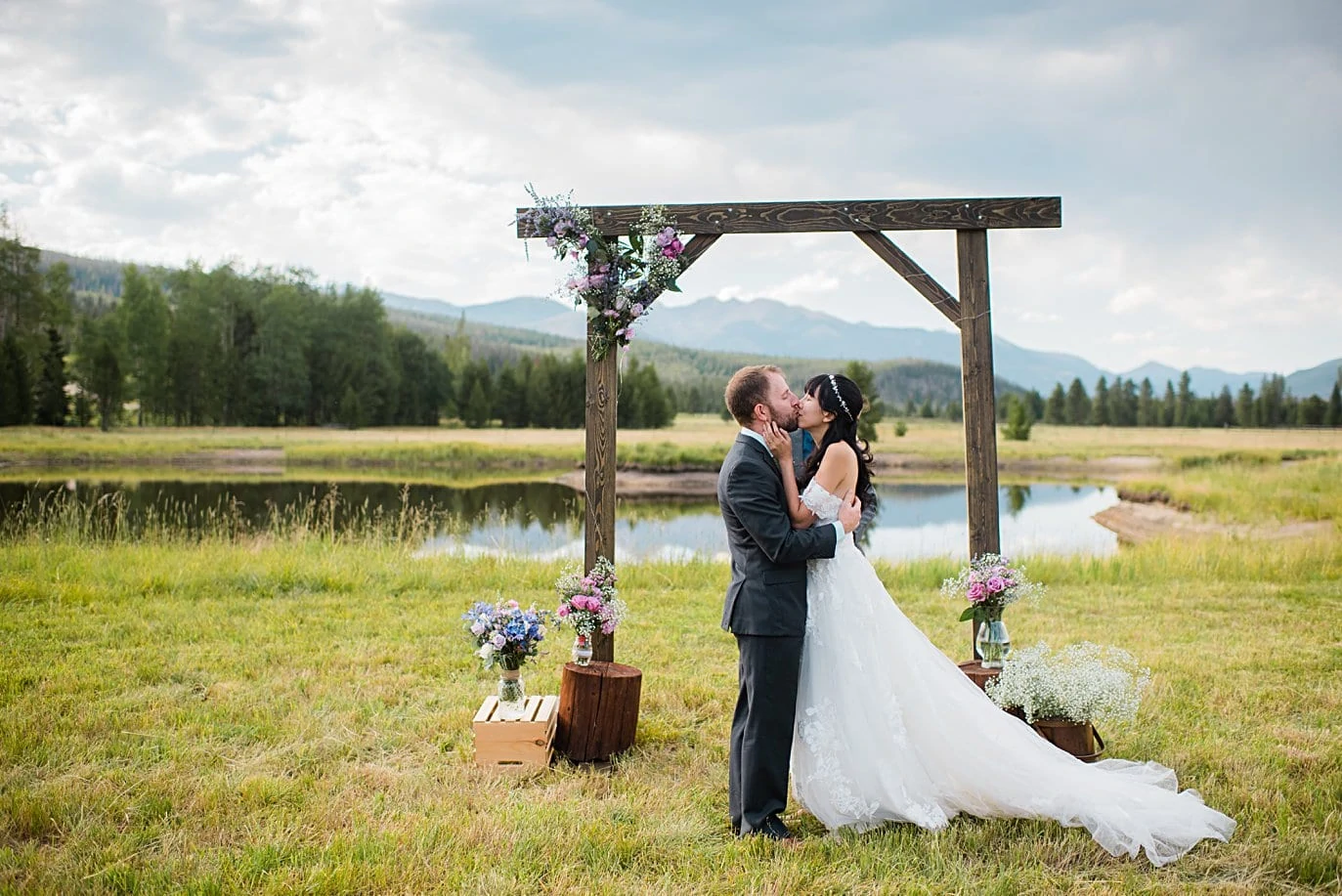 bride and groom first kiss in outdoor Colorado mountain ceremony at intimate Grand Lake wedding by Estes Park wedding photographer Jennie Crate