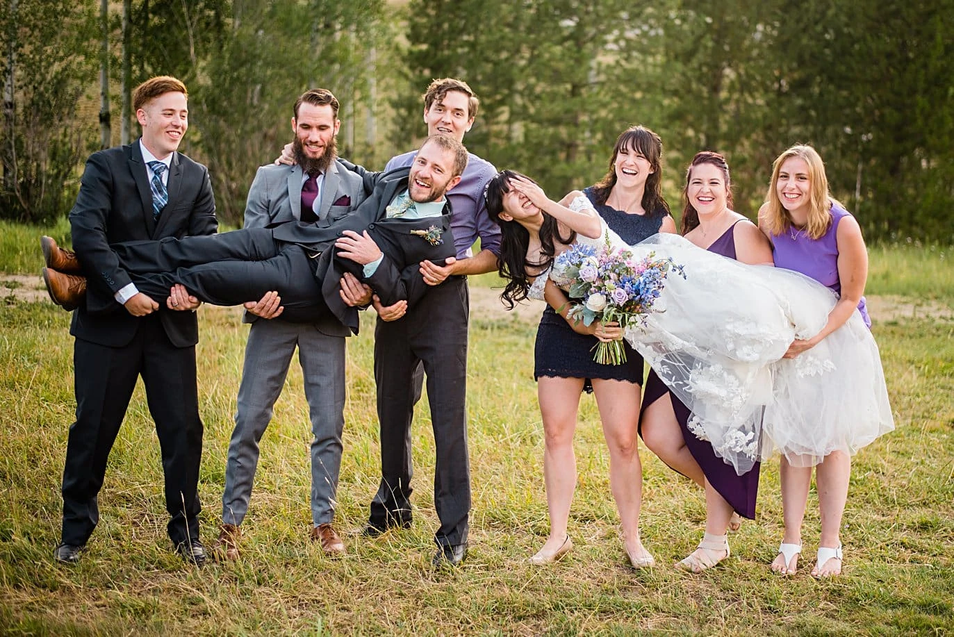 friends lift bride and groom after outdoor Colorado mountain ceremony at intimate Grand Lake wedding by Estes Park wedding photographer Jennie Crate