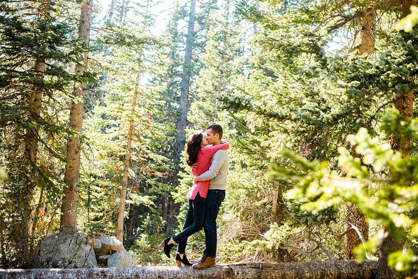 couple kisses on top of log during Colorado engagement hike by Denver engagement photographer Jennie Crate