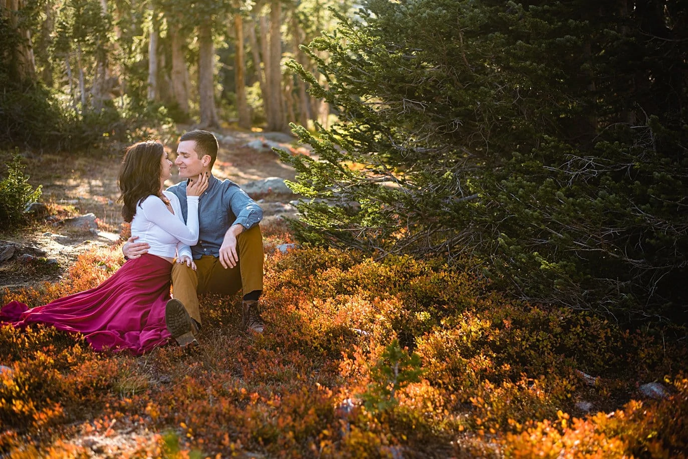 couple cuddles in orange fall foliage during fall engagement hike by Boulder engagement photographer Jennie Crate