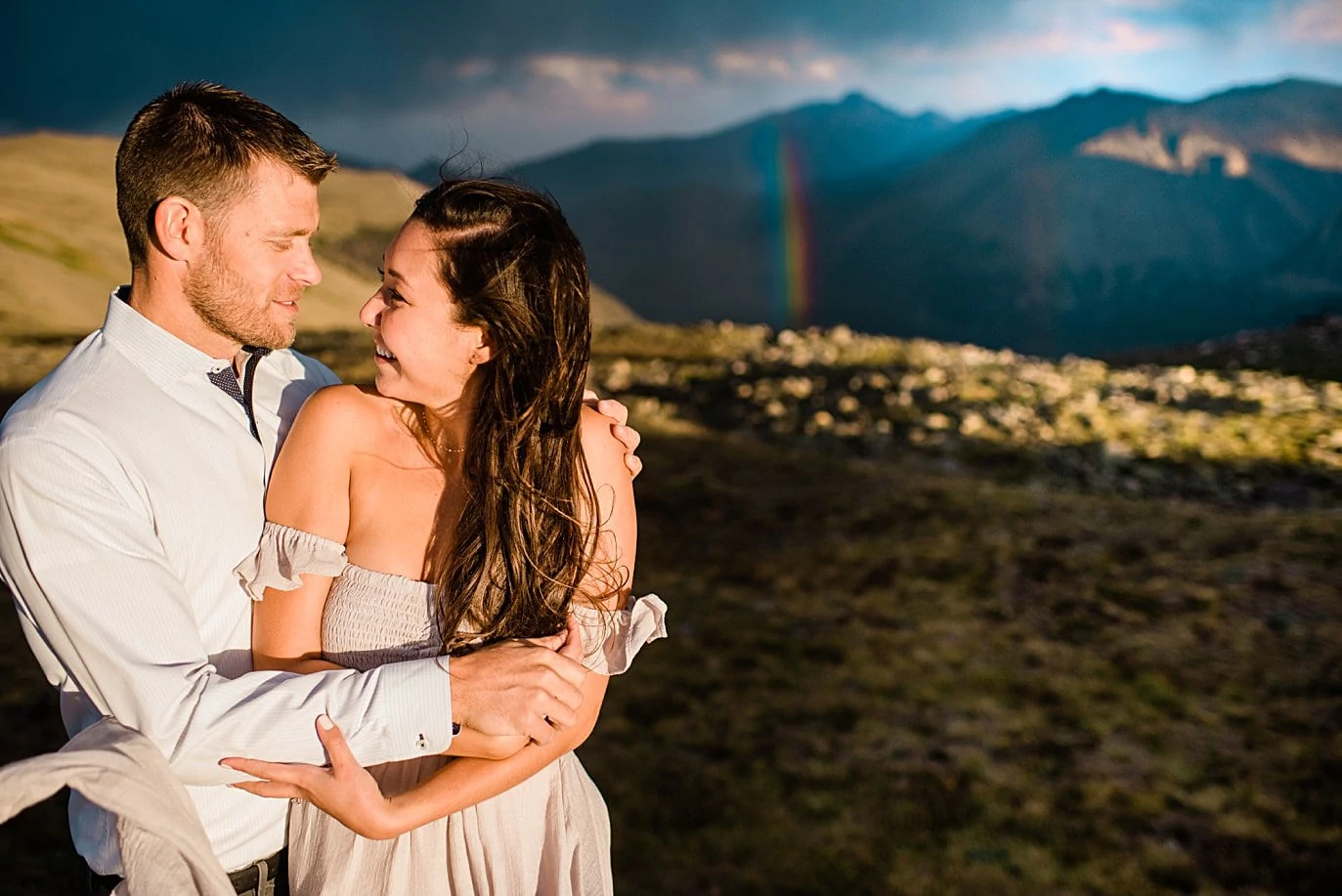 bride and groom in boho attire with rainbow at top of trail ridge road during engagement session by Estes Park engagement photographer Jennie Crate