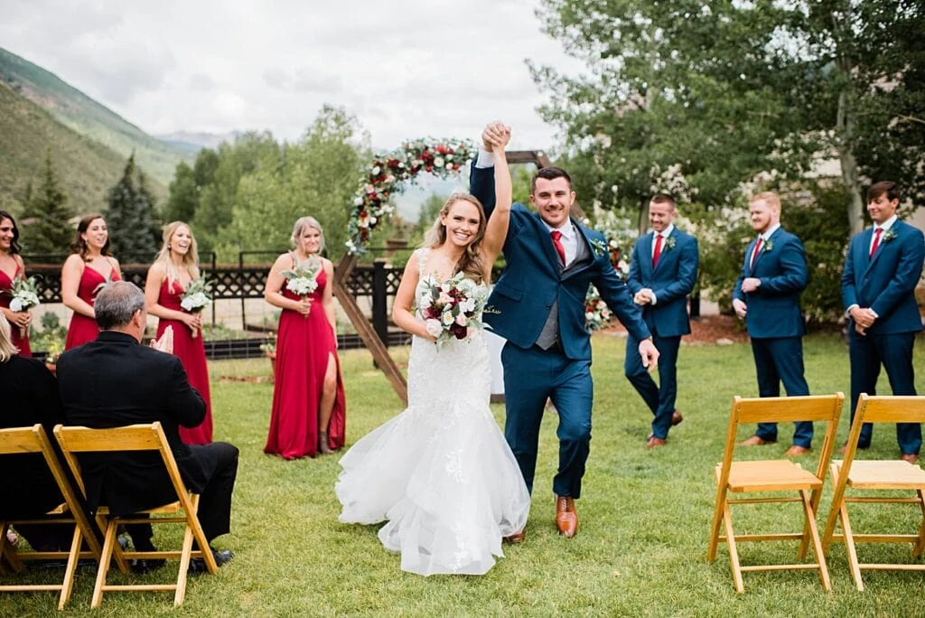 bride and groom are cheered down the aisle after wedding ceremony at Larkspur Vail Wedding by Lyons Wedding photographer Jennie Crate