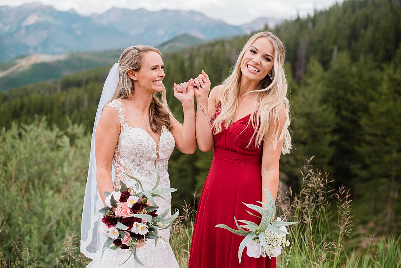 bride and bridesmaid pinky promise at top of Vail mountain at Vail Manor Lodge wedding by Breckenridge wedding photographer Jennie Crate