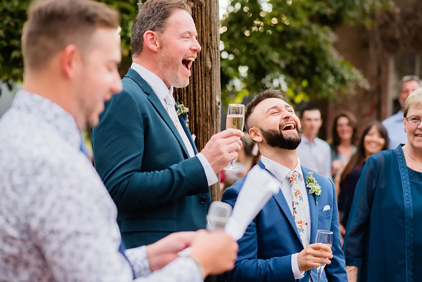 grooms laughing during toasts at Denver gay wedding