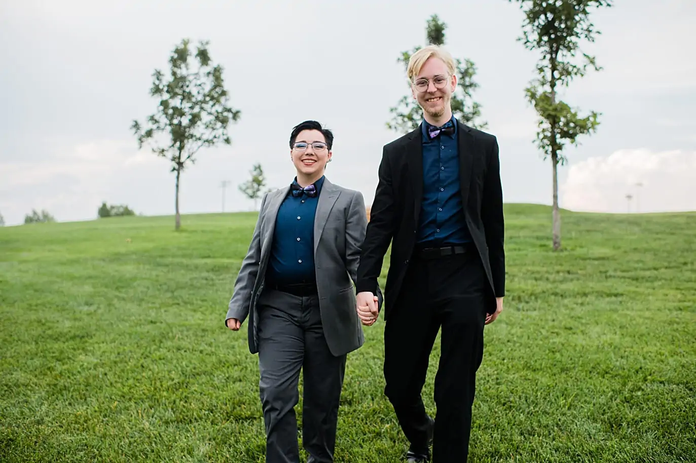 Queer couple walk hand in hand in suits at LGBTQ wedding in Fort Collins