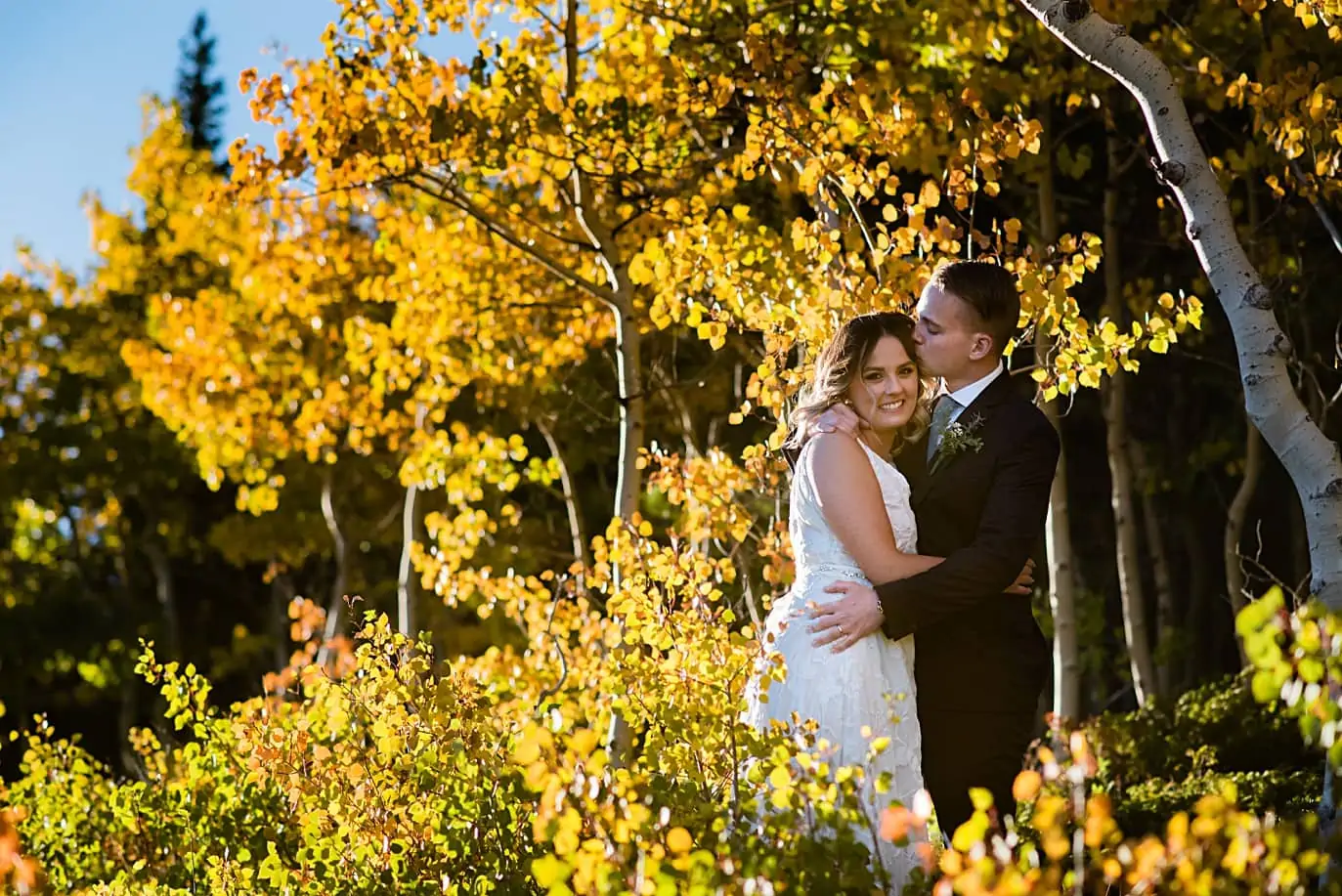 bride and groom cuddle in the fall aspen trees that are yellow after their Long Lake elopement
