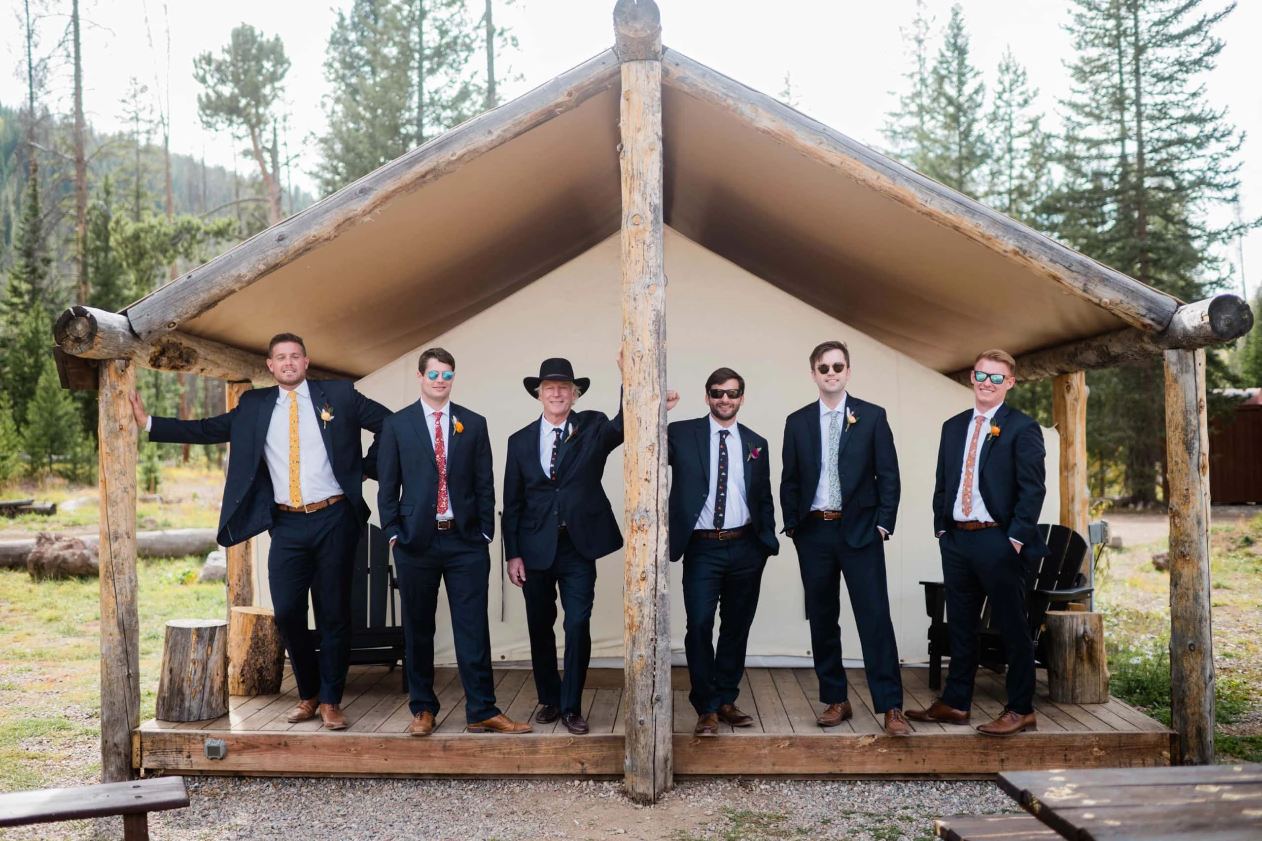 groom and groomsmen pose at glamping tents at Piney River Ranch wedding