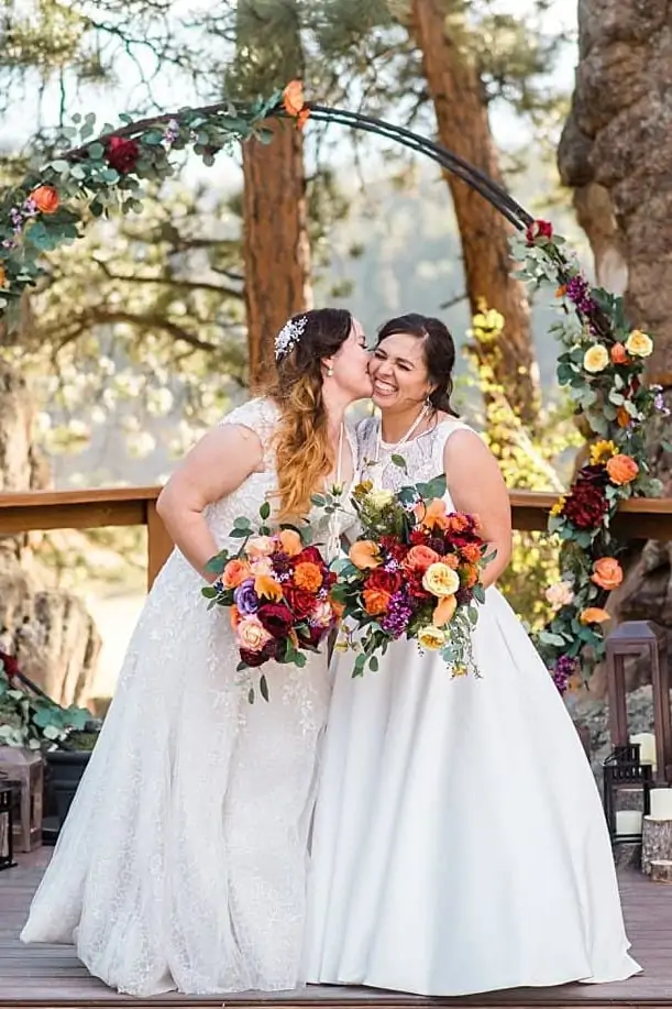 two brides in dresses at ceremony spot at the homestead at LGBT wedding by Colorado LGBT wedding photographer Jennie Crate