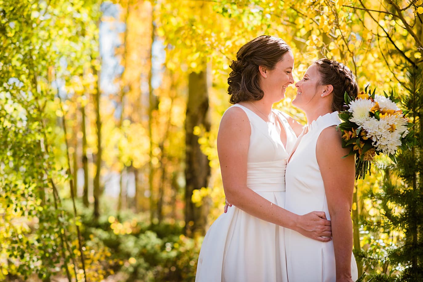 two brides in the yellow aspens at their fall wedding in breckenridge co