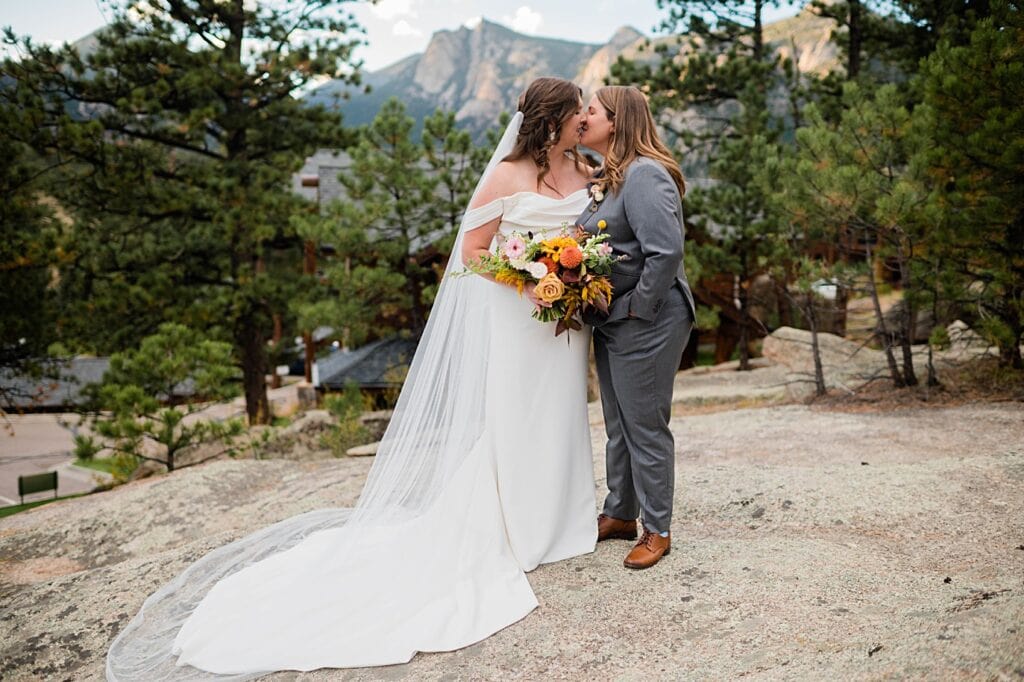 Two brides share a kiss in front of the Estes park mountains at The Boulder wedding