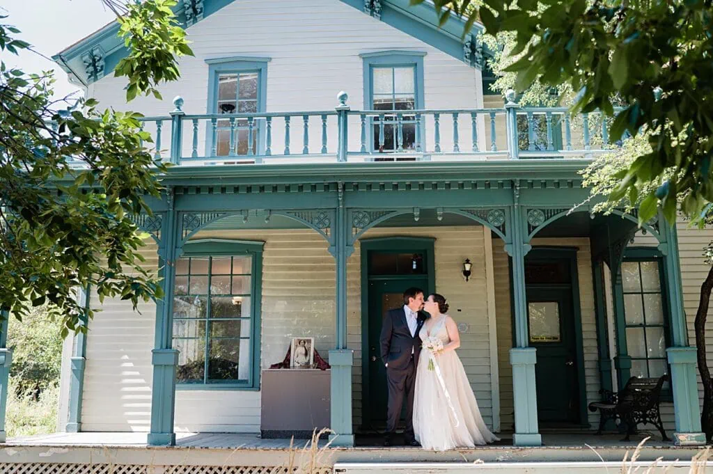 bride and groom kiss in front of the historic house on 9th street park at their tivoli auraria campus wedding in Denver