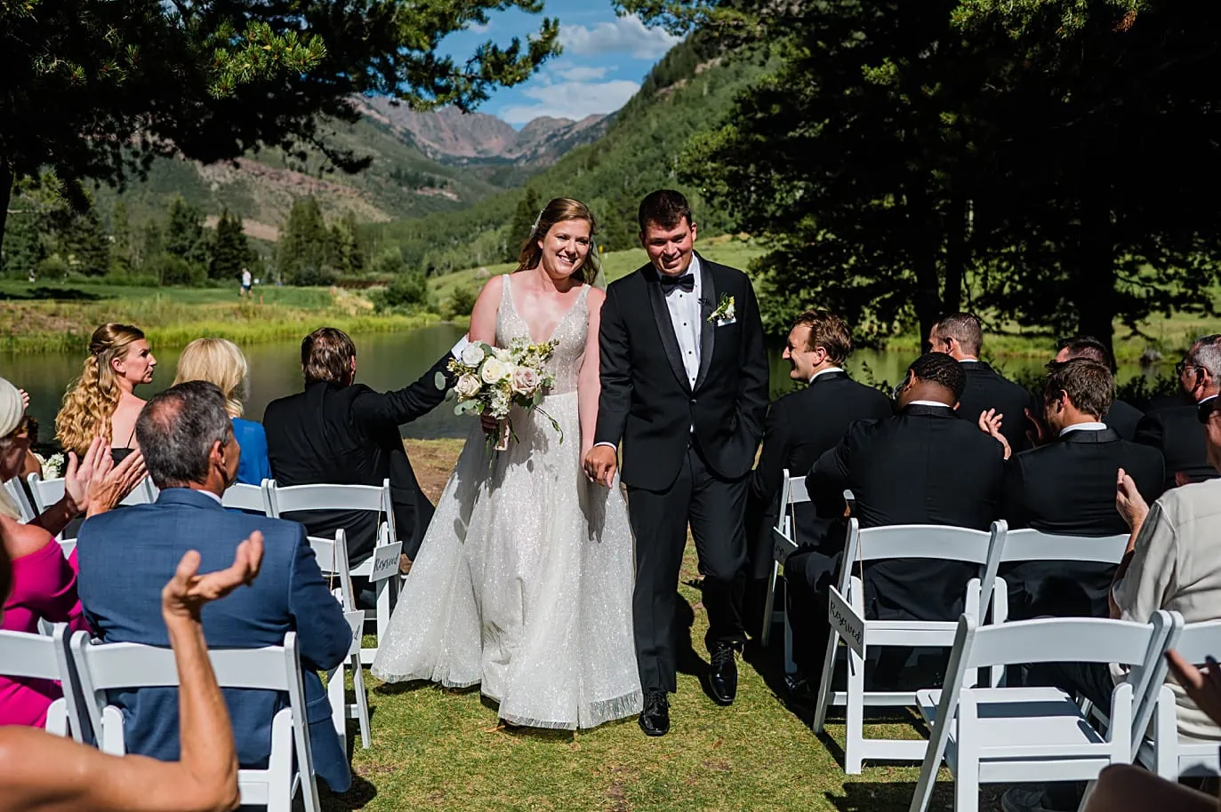 bride and groom walk back up aisle after ceremony on wedding island at vail golf club wedding