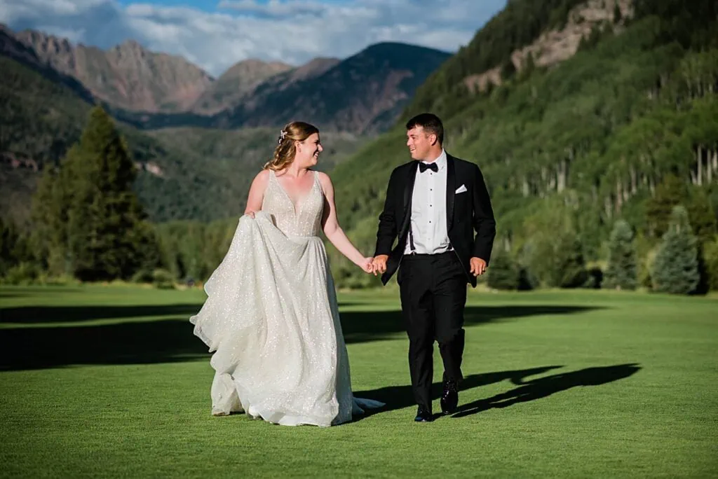 bride and groom walk hand in hand on Vail Golf Course at their Vail Golf Club wedding