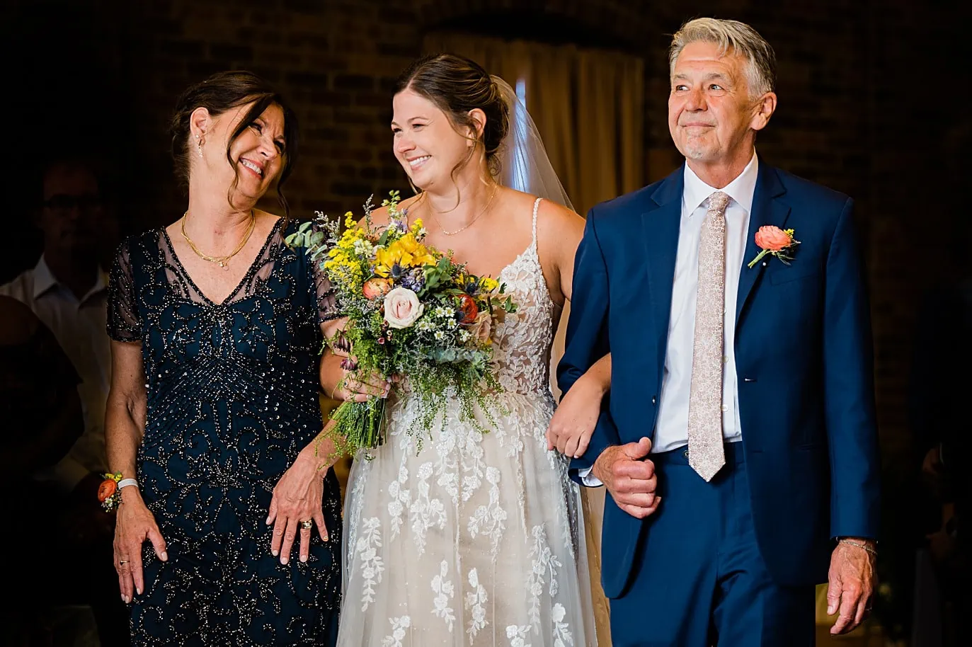 bride walks down the aisle with parents at upper larimer wedding in summer